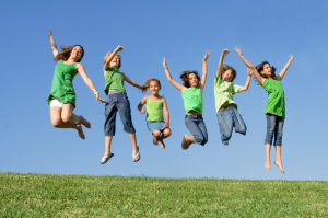 Happy group of mixed race kids at summer camp or school jumping